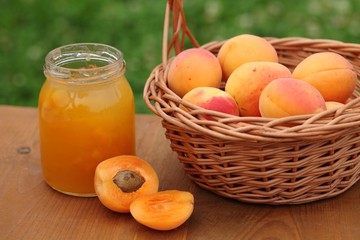 Glass with apricot jam and fresh apricots in basket