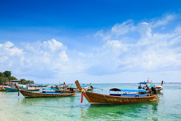 Naklejka na ściany i meble Wooden boats on the beach with the blue sky and sea