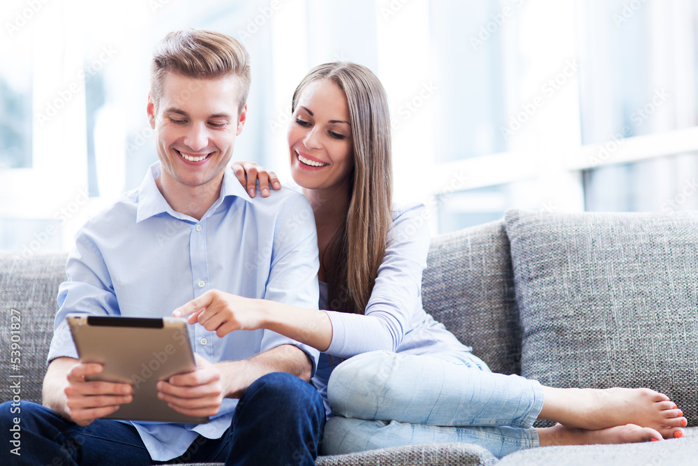 Wall mural couple on sofa with digital tablet