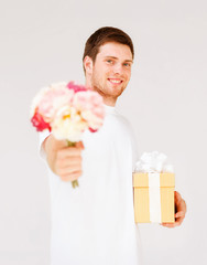 man holding bouquet of flowers and gift box
