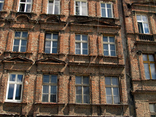Naklejka premium wall with windows of an old, damaged residential building in Wro