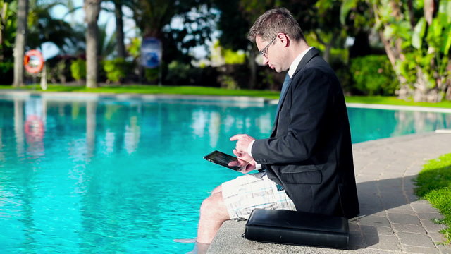 Portrait of smiling businessman with tablet computer by the swim