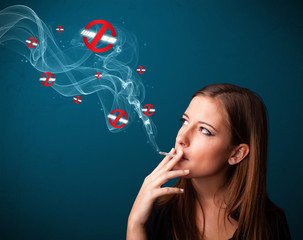 Obraz premium Young woman smoking dangerous cigarette with no smoking signs