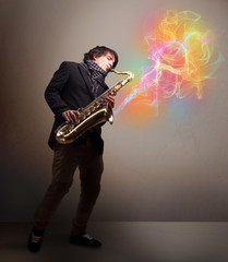 Fototapeta na wymiar Attractive musician playing on saxophone with colorful abstract