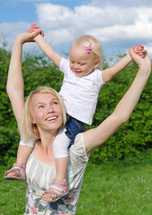 Fototapeta premium Happy mother carrying her daughter on shoulders