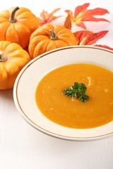 Plate with pumpkin soup and autumn decorations.