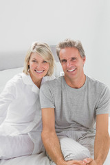 Smiling couple sitting on bed