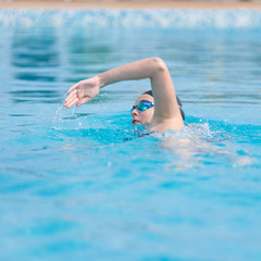 Woman in goggles swimming front crawl style