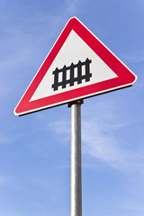 Railroad crossing sign with a barrier over blue sky