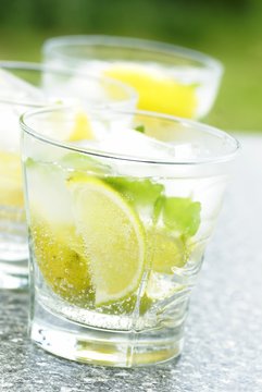 Fresh drink with ice cubes, lemon, lime and mint