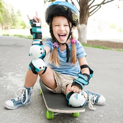 Tuinposter little girl sitting on a skateboard © tan4ikk