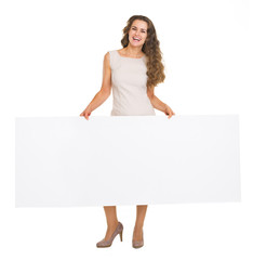 Full length portrait of happy woman showing blank billboard