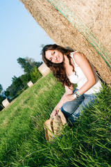 Naklejka na ściany i meble Portrait of a girl next to a stack of hay