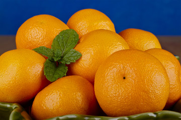Bowl of fresh clementines on a blue background