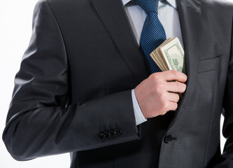 A businessman in a black suit putting money in his pocket