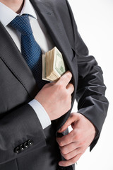 A businessman in a black suit putting money in his pocket