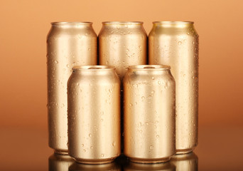 Aluminum cans with water drops on color background