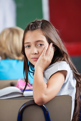 Schoolgirl Leaning On Chair In Classroom