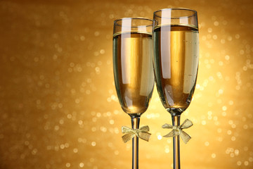 Two glasses of champagne on bright background with lights