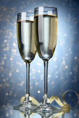 Two glasses of champagne on bright background with lights