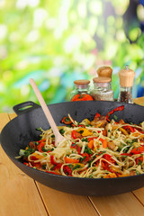 Noodles with vegetables on wok on nature background background