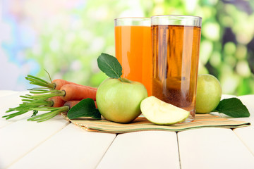 Glasses of juice, apples and carrots