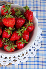 Strawberries in plate on wicker stand on napkin close-up