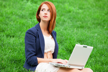 Redhead girl at green grass with notebook