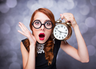Surprised redhead girl with clock.