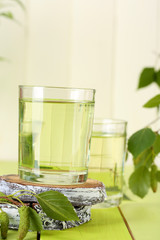 Glasses of birch sap on green wooden table