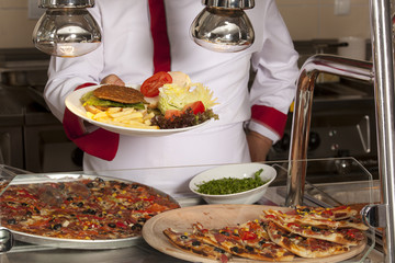 chef standing behind burger,spaghetti and pizza station
