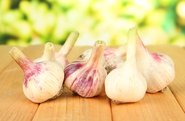Fresh garlic on wooden table, on bright background