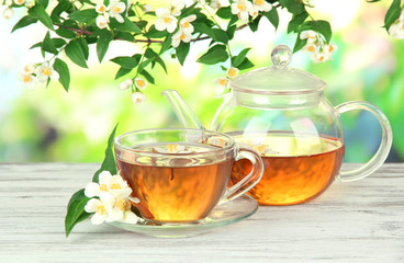 Cup of tea with jasmine, on wooden table, on bright background