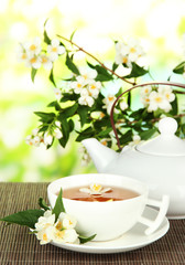 Cup of tea with jasmine, on bamboo mat, on bright background