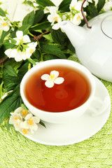 Cup of tea with jasmine, on wicker mat background