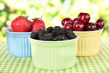 Ripe mulberries with cherry and strawberries in bowls