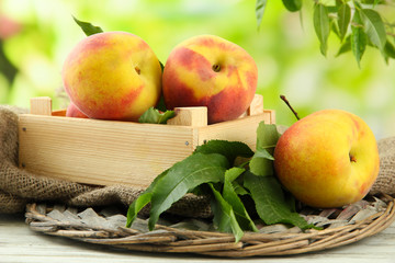 Ripe sweet peaches in wooden crate, outside