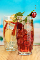 Glasses of fruit drinks with ice cubes on blue background