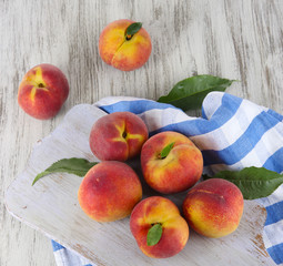 Peaches on board on napkin on table on wooden background
