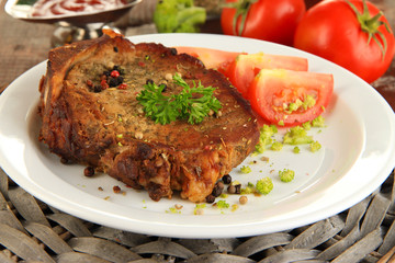 Piece of fried meat on plate on wooden table close-up