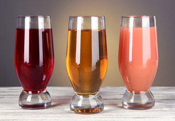 Glasses of fresh juice on table on gray background