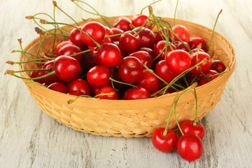 Cherry berries in wicker basket on wooden table close up