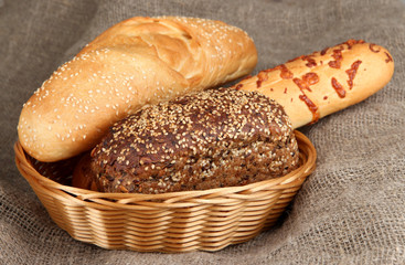 Baked bread in wicker basket on burlap background