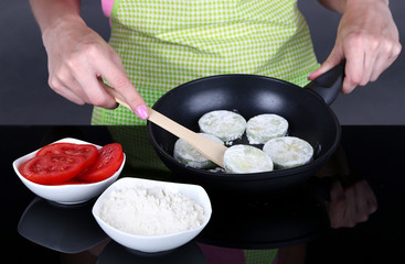 Hands cooking marrows in pan on gray background
