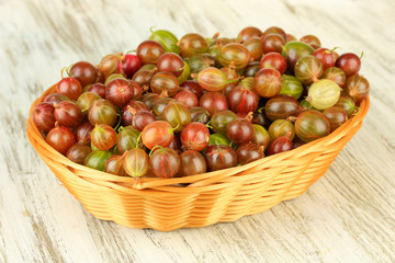 Fresh gooseberries in wicker basket on table close-up
