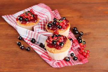 Tasty muffins with berries on wooden table