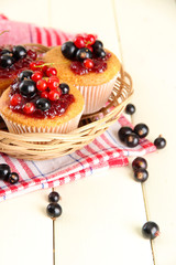 Tasty muffins with berries on white wooden table