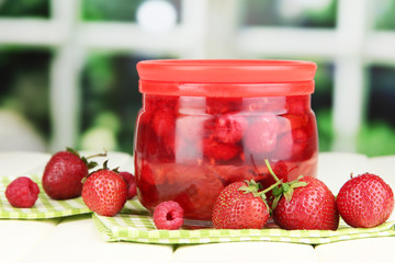 Home made berry jam on wooden table on window background