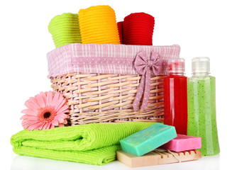Colorful towels in basket, cosmetics bottles and soap, isolated