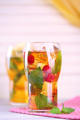 Iced tea with raspberries, lemon and mint on wooden table